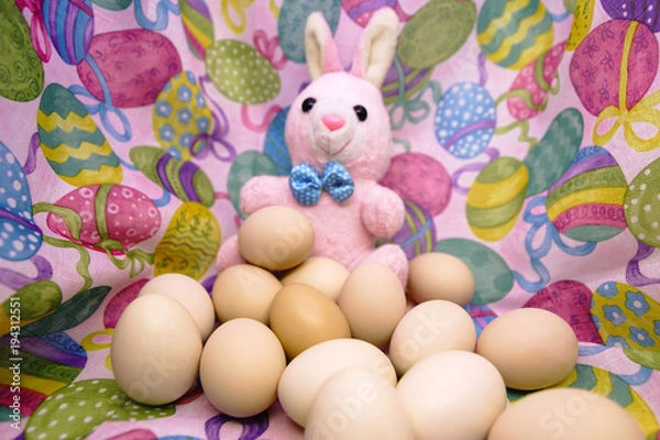 Fototapeta Easter bunny and raw eggs on a colored background