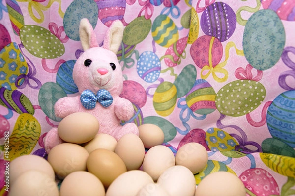 Fototapeta Easter bunny and raw eggs on a colored background