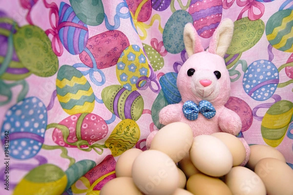 Fototapeta Easter bunny and raw eggs on a colored background