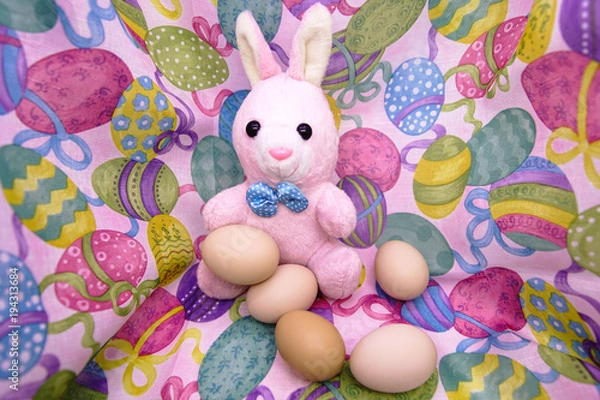 Fototapeta Easter bunny and raw eggs on a colored background