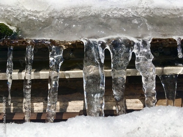 Obraz eiszapfen in einer reihe von einem schneebedeckten dach hängend/wasser zu eis gefroren, gebilde in der natur/kalte winterzeit, starre strukturen