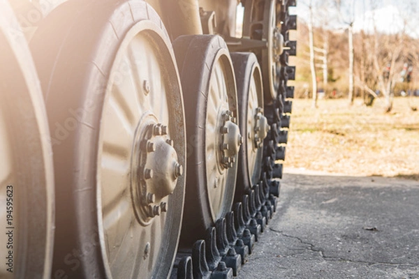 Fototapeta Caterpillar of a military tank standing in a park.