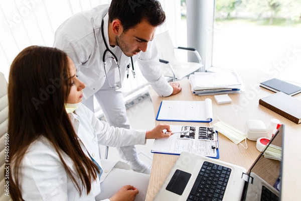 Fototapeta Young doctors looking at paperboard