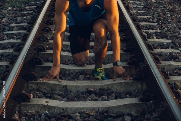 Fototapeta Close up the runner start from run on railroad tracks with dramatic tone, Sunset running in the evening