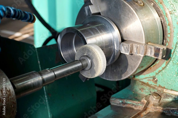 Obraz Spindle with an abrasive circle for intra grinding work on the grinder. Dry grinding by a circle end face by a long frame and thin white stone. There grinding inner sleeve hole.