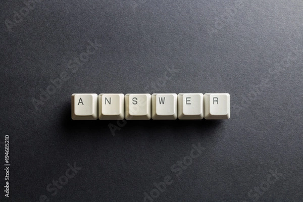 Fototapeta Word answer made using computer keyboard buttons on a black background. IT technology concept.