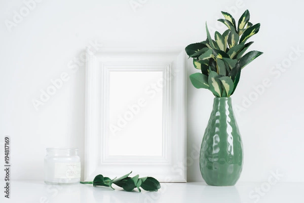 Fototapeta White frame mockup with yellow-green leaves and candle