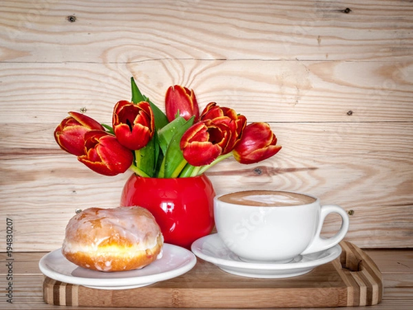 Fototapeta A cup of cappuccino, donut and a bouquet of tulips in a red vase. Mother's Day and Women's Day celebration