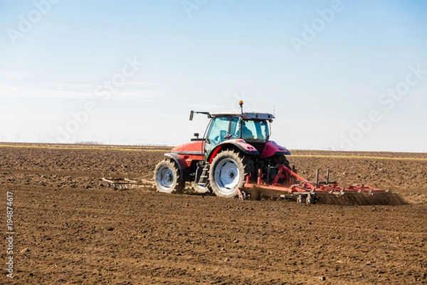 Fototapeta Farmer in tractor preparing land with seedbed cultivator as part of pre seeding activities in early spring season of agricultural works at farmlands.