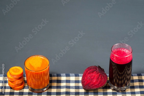 Fototapeta Natural juices from carrots and beets. The juice stands on a tablecloth, next to sliced carrots and beets. Tasty and healthy juice.