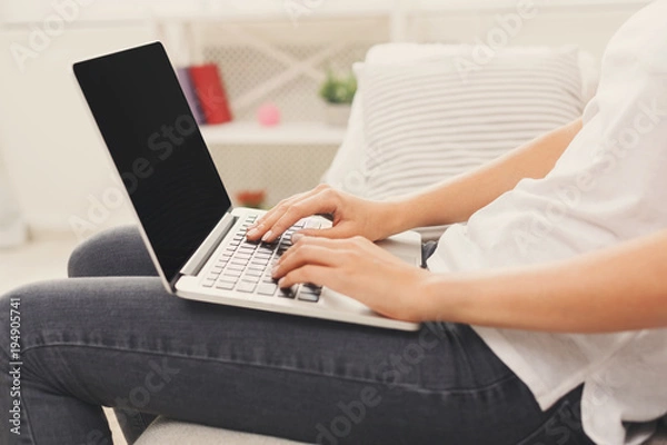 Fototapeta Unrecognizable girl with laptop sitting on the sofa