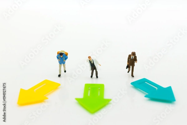 Fototapeta Miniature people: Guys standing on front of arrow pathway choice. Image use for Business decision concept.