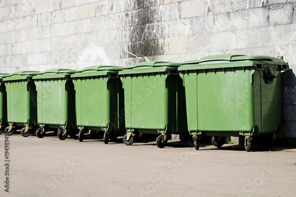 Fototapeta A row of green garbage containers on the city street.