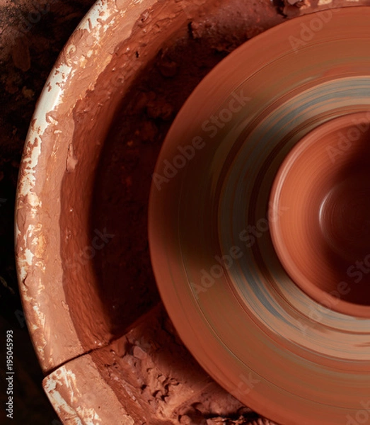 Fototapeta production process of pottery. mug of red clay on a potter's wheel.