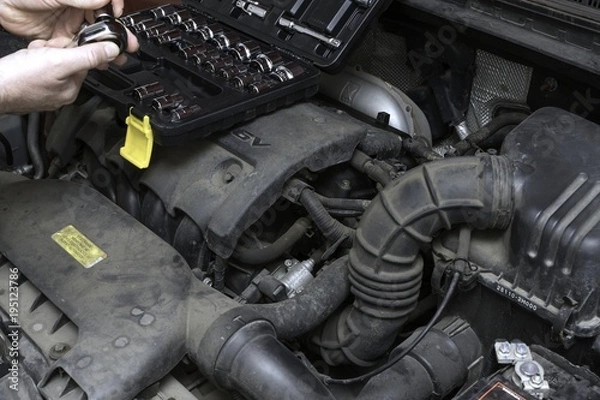 Obraz the car mechanic fixes the car engine by tools
