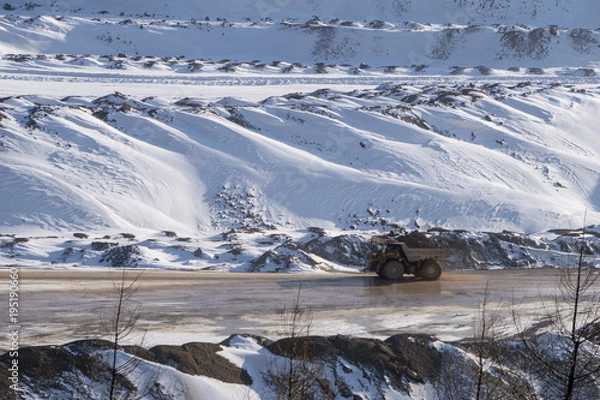 Fototapeta Loaded haul truck driving on a muddy road at an open pit mine in winter