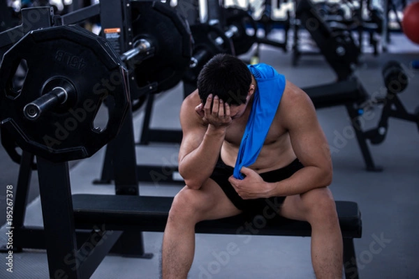 Fototapeta Tired man taking a workout rest. Male athlete suffering a headache or dizziness. Unmotivation in sport and tiredness concept. 