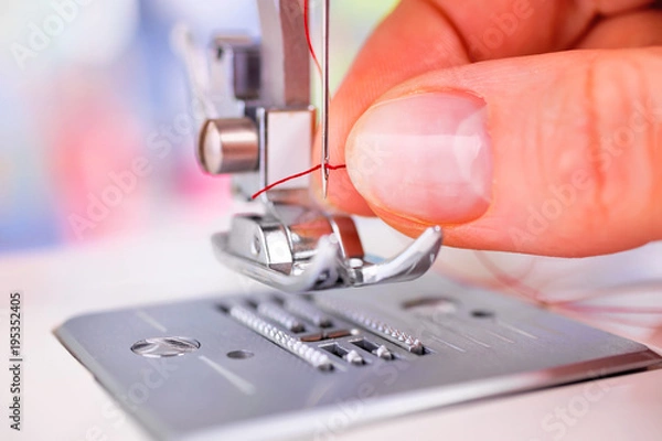 Fototapeta Woman's hand threading sewing machine needle