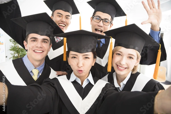 Fototapeta happy graduates making selfie photo in classroom.