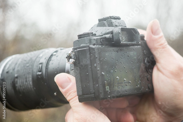 Fototapeta A photographer with a camera in the rain