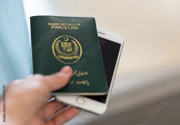 Obraz A hand holds Pakistan passport. Focus on the font on passport