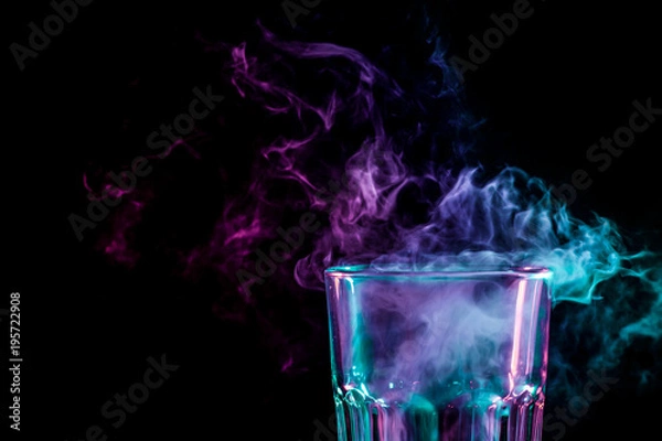 Fototapeta Close up of a new glass with soft multi-colored purple and green smoke from vape on a black isolated background