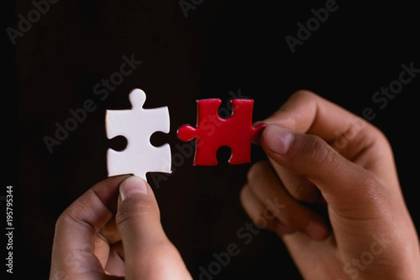 Fototapeta Hands trying to fit two puzzle pieces together