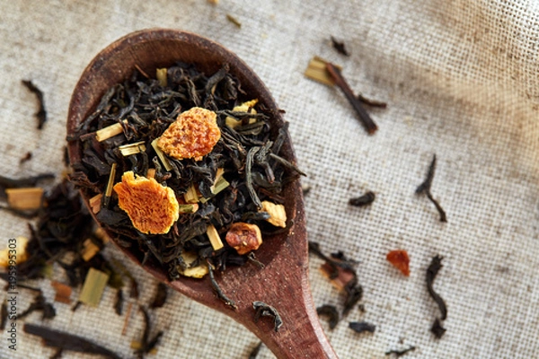 Fototapeta Closeup of a wooden spoon filled with scattered tea leaves, shallow depth of field, top view