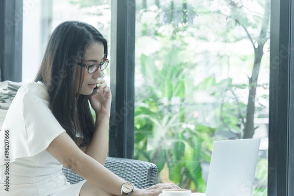 Fototapeta Beautiful asian attractive woman has working and talking with phone for business marketing at coffee cafe in the morning with happy and relaxing time.