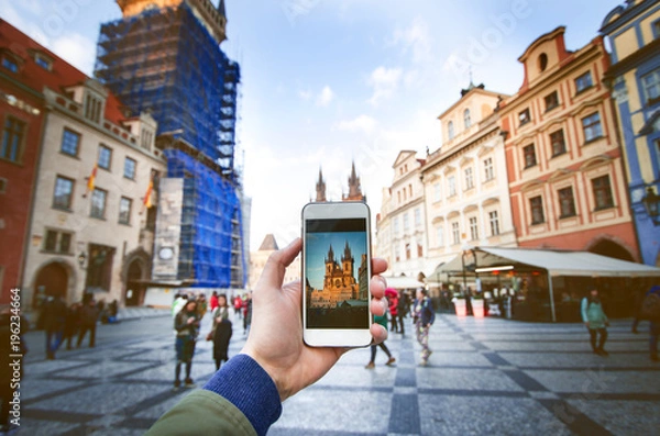 Fototapeta Aparat fotograficzny smartfona i starego centrum Pragi ze słynnym zwiedzaniem. Rynek Starego Miasta z ludźmi podczas zachodu słońca