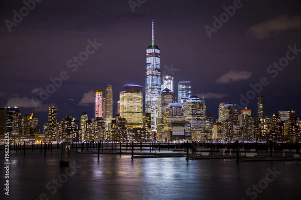 Fototapeta The lights of Lower Manhattan and the World Trade Center reflect off the water of the Hudson River, as seen from Hoboken, New Jersey.