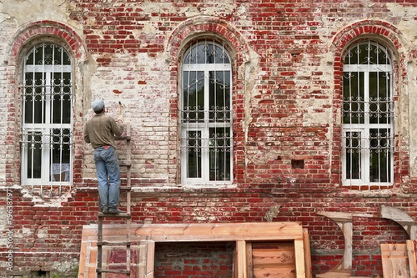 Fototapeta Working restorer restores the old wall of the building. Texture of old brick wall.