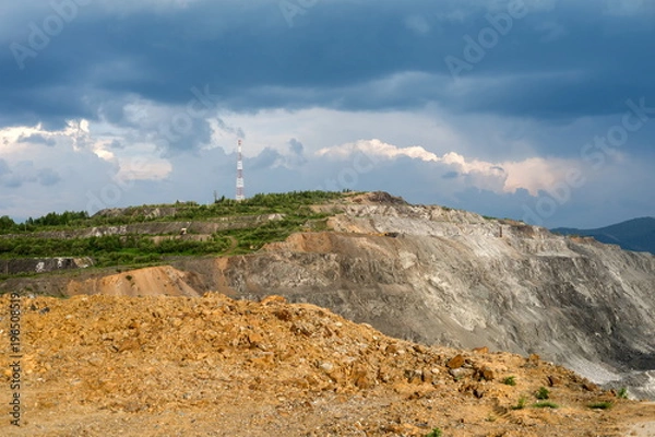 Fototapeta The cell tower stands on a hill above the bench slopes of the open-pit mine. The quarry operation  is located in the village of Belogorsk, Kemerovo region. Siberia, Russia.
