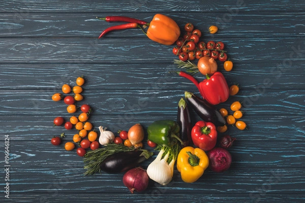 Fototapeta top view of round of ripe organic vegetables on wooden table