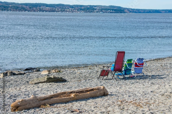 Fototapeta Three Colorful Folding Beach Chairs and Driftwood