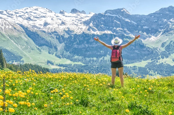 Fototapeta Swiss Alps. Girl standing on a flowering meadow, arms outstretched and admiring the mountain scenery. Engelberg Resort