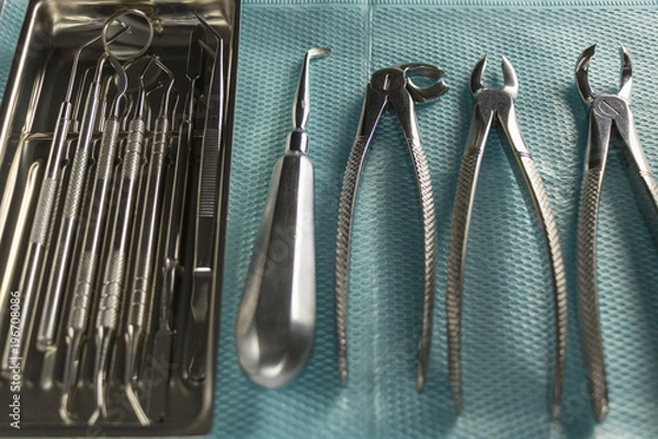 Fototapeta a medical tray with dental instruments, a mirror and a probe. surgical instruments for tooth extraction. medical blue napkin. background