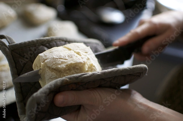 Obraz Slicing warm bread with bread knife