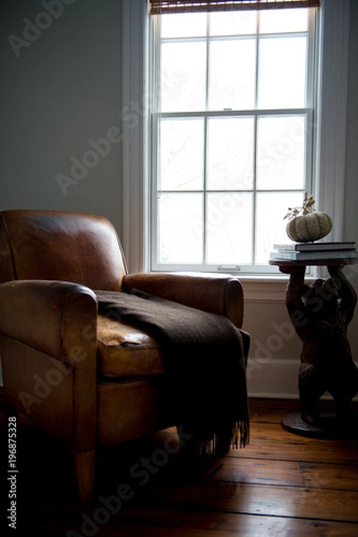Fototapeta Old leather chair by the window with a stand on a side 