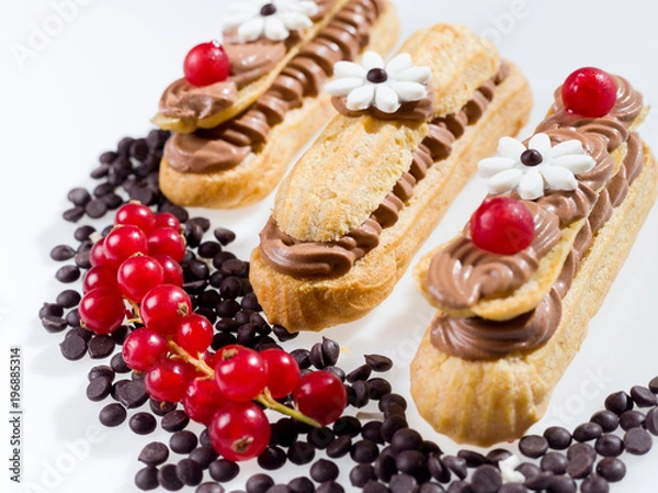 Fototapeta Eclairs with chocolate bits and currant