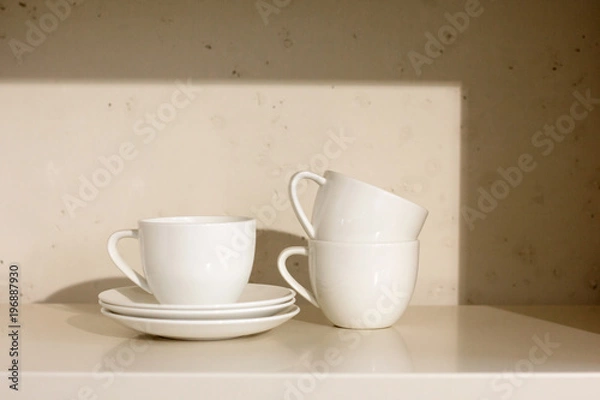 Fototapeta białe ceramiczne filiżanki i spodek na półce