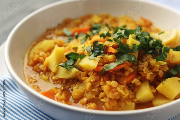 Fototapeta Red lentil stew with potato, carrot and turmeric. Toned photo. Healthy lunch on the round white plate. Colorful vegan dish with potato, carrot and turmeric. European cuisine. Vegetarian.
