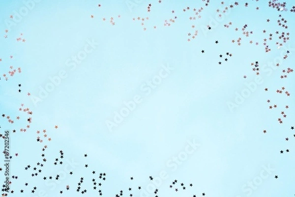 Fototapeta Star shaped silver sequins over blue background. Copy space.