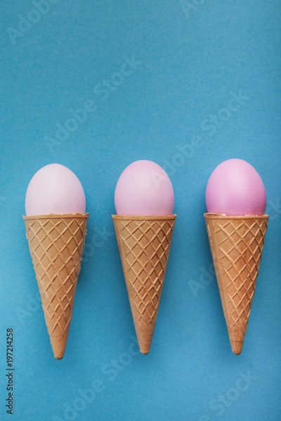 Fototapeta Pink easter eggs in waffle cones on blue background