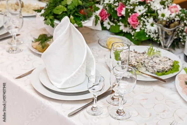 Obraz сервировка стола с белыми тарелками с салфетками и фужерами 