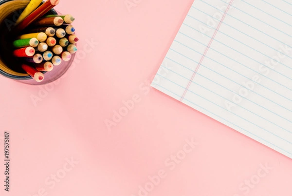 Fototapeta A cup with colored pencils and a white notepad on a flat pink surface