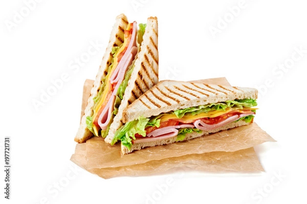 Fototapeta Sandwich with ham, cheese, tomatoes, lettuce, and toasted bread. Above view isolated on white background.