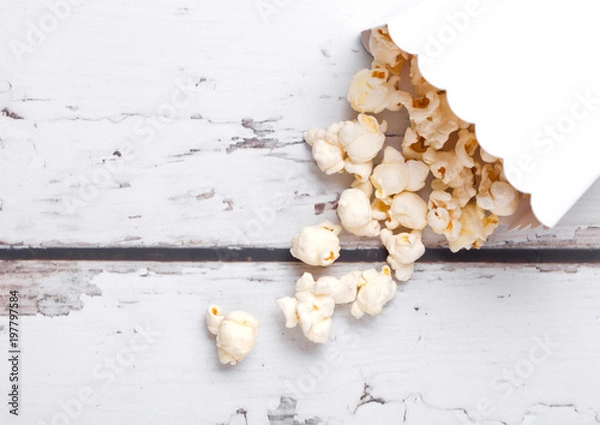Fototapeta Paper container with fresh salted popcorn on wood