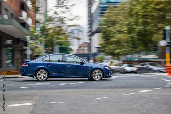 Obraz Blue car in motion on the road, Sydney, Australia. Car moving on the road, blurred buildings in background.