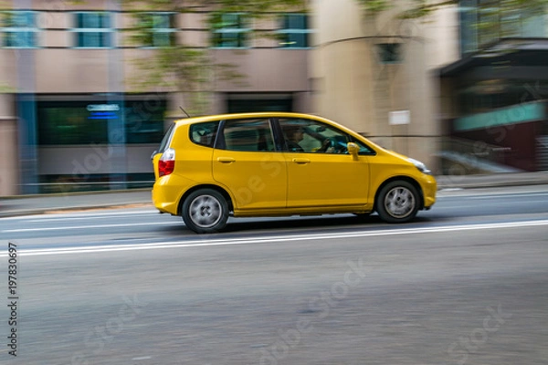 Obraz Yellow car in motion on the road, Sydney, Australia. Car moving on the road, blurred buildings in background.